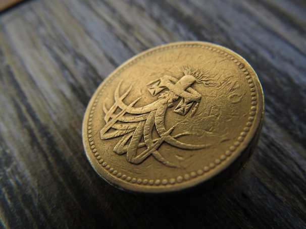 Close-up of a ceremonial gold coin glowing softly against a dark background.