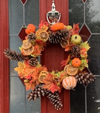 A vibrant autumn wreath hanging on a rustic wooden door.