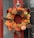 Close-up photo of a vibrant autumn wreath hanging on a rustic wooden door.