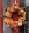 Close-up photo of a vibrant autumn wreath hanging on a rustic wooden door.