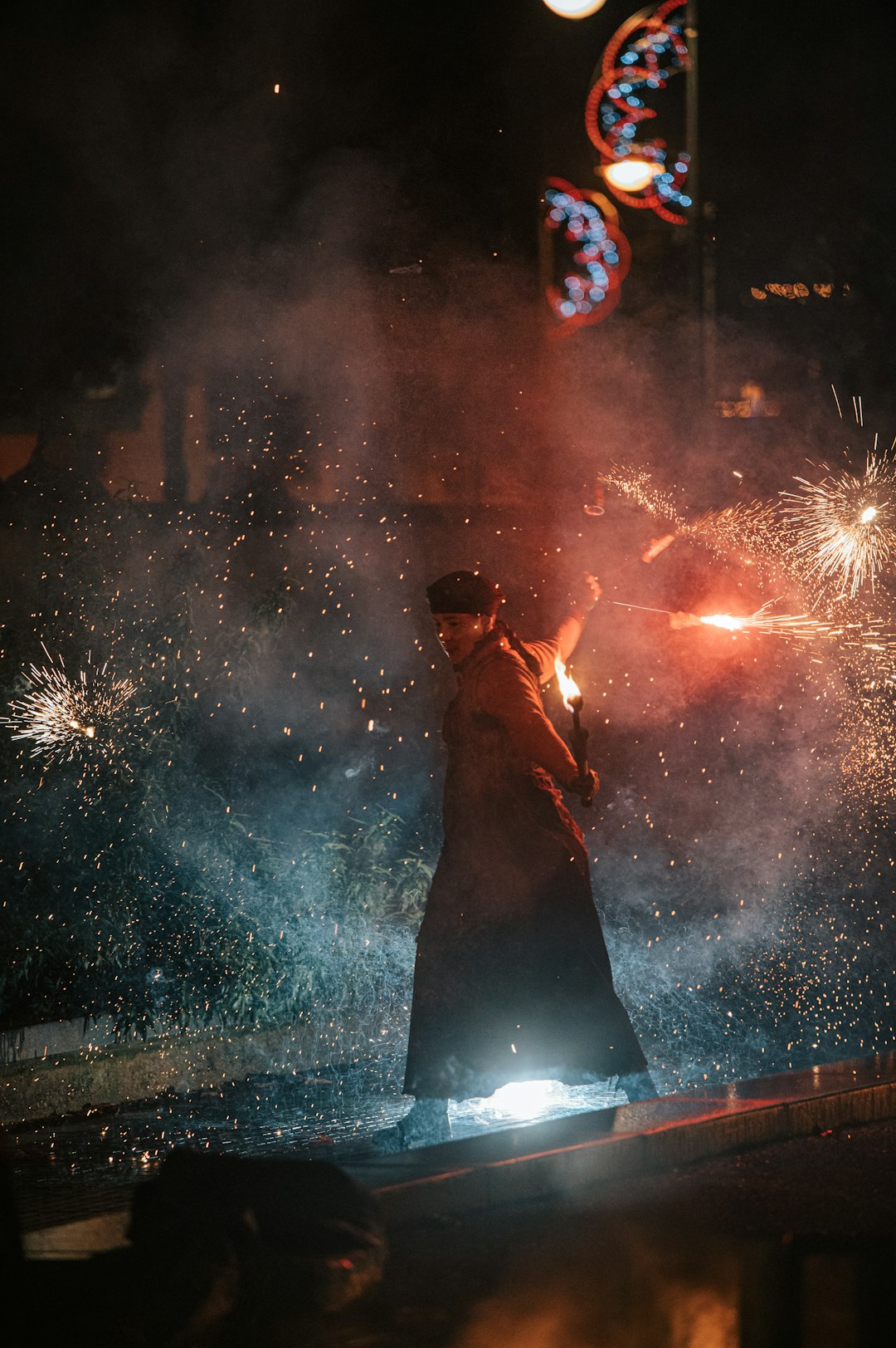 man in black shirt standing on the street with fireworks display