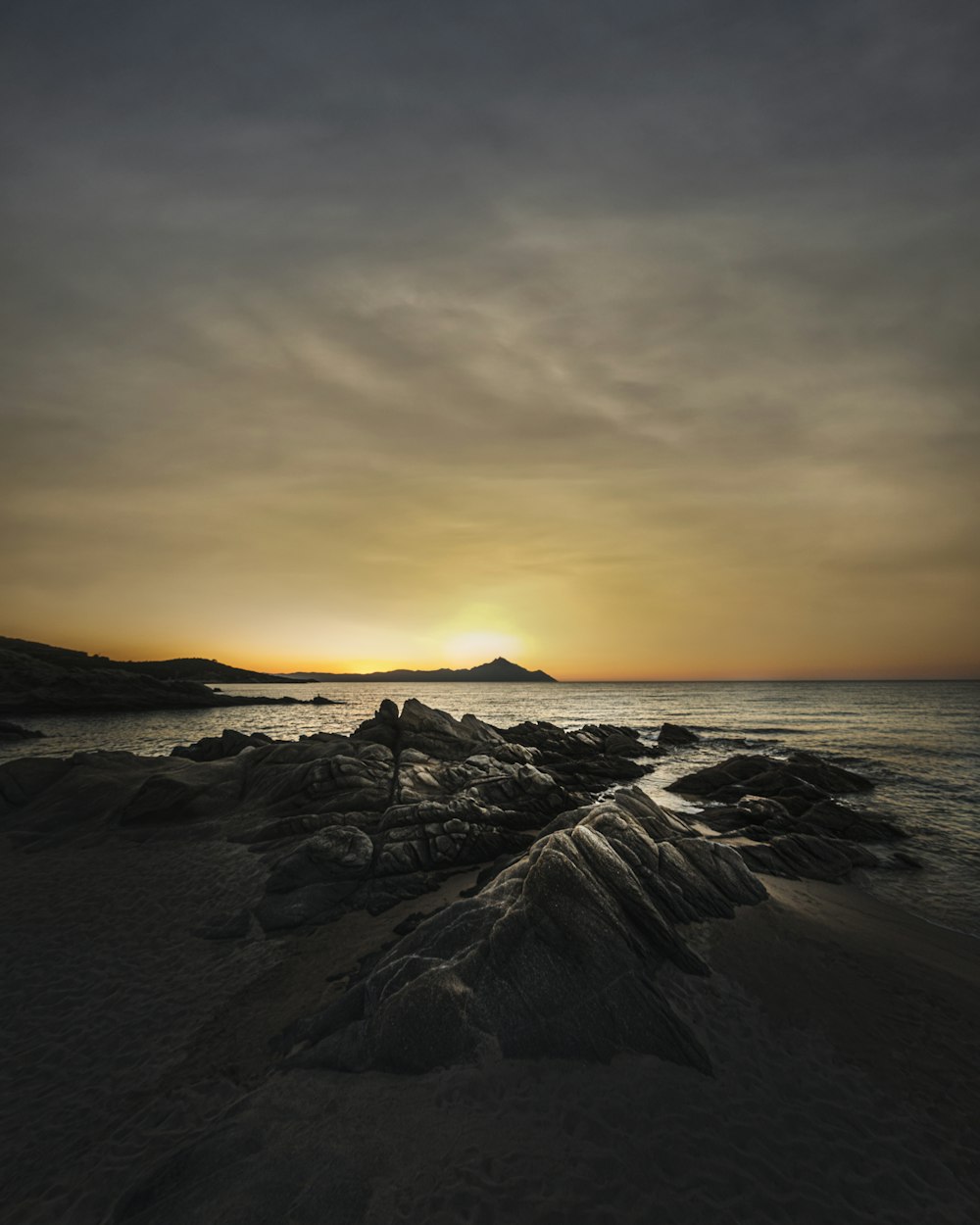 日没時の海岸の黒い岩層
