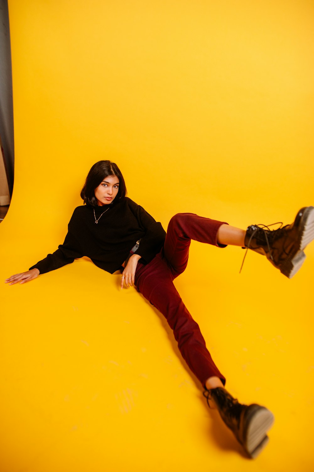 woman in black hijab and orange pants sitting on yellow wall