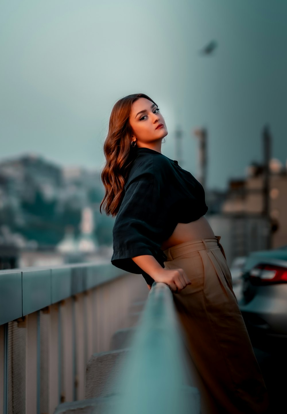 woman in black jacket and brown pants standing on bridge during daytime