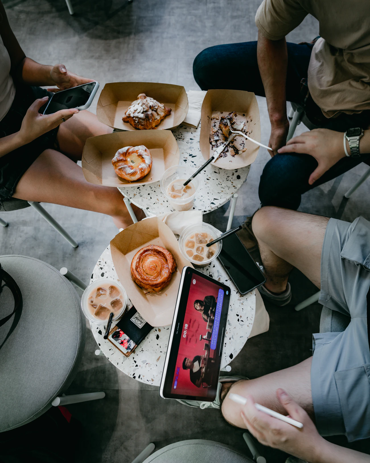 A small café table topped with fresh pastries and lattes, shot from above