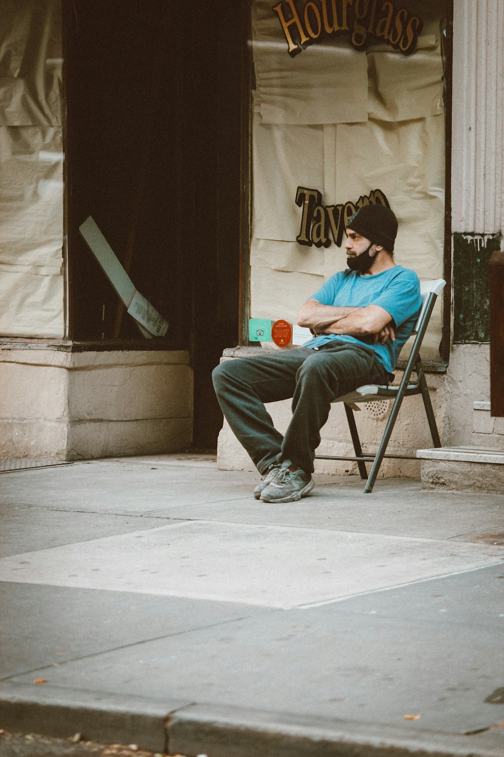 man in blue jacket and blue denim jeans sitting on brown wooden folding chair