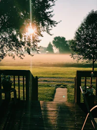 A serene backyard showing a spacious wooden deck surrounded by mature trees and well-maintained garden beds.