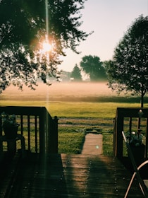 A serene backyard with a wooden deck, outdoor seating, and well-maintained lawn under soft daylight.