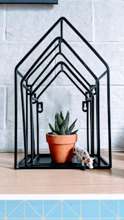 An industrial metal plant stand with a matte black finish showcasing a blooming succulent.