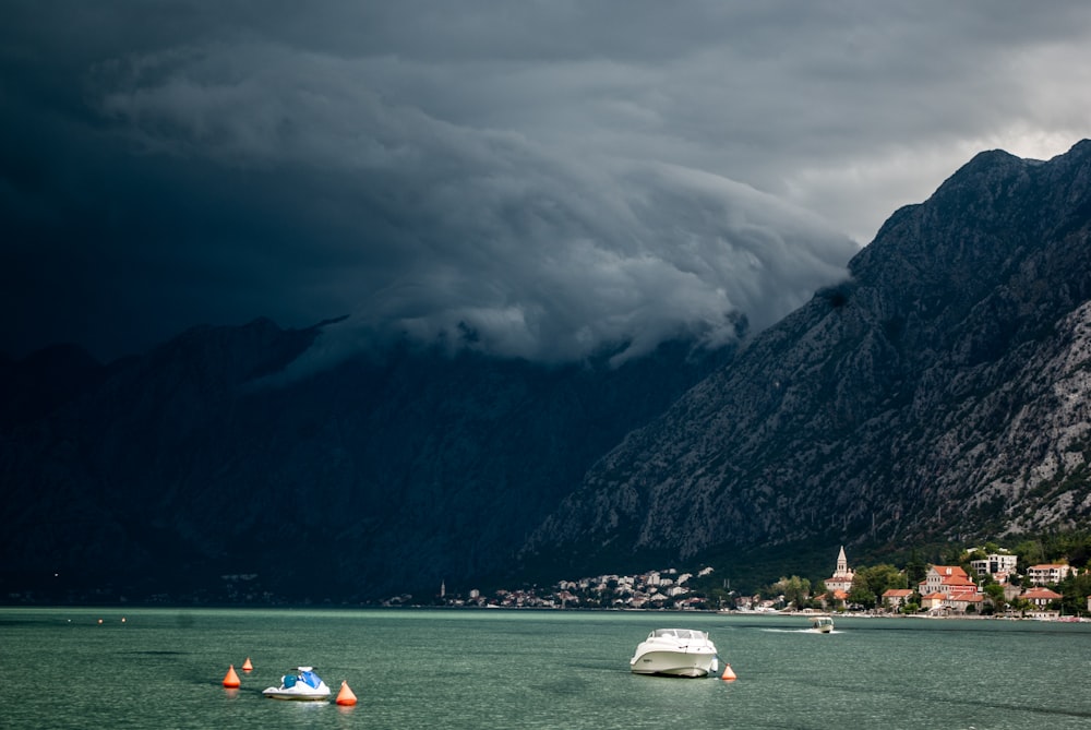 people riding on boat on sea near mountain during daytime