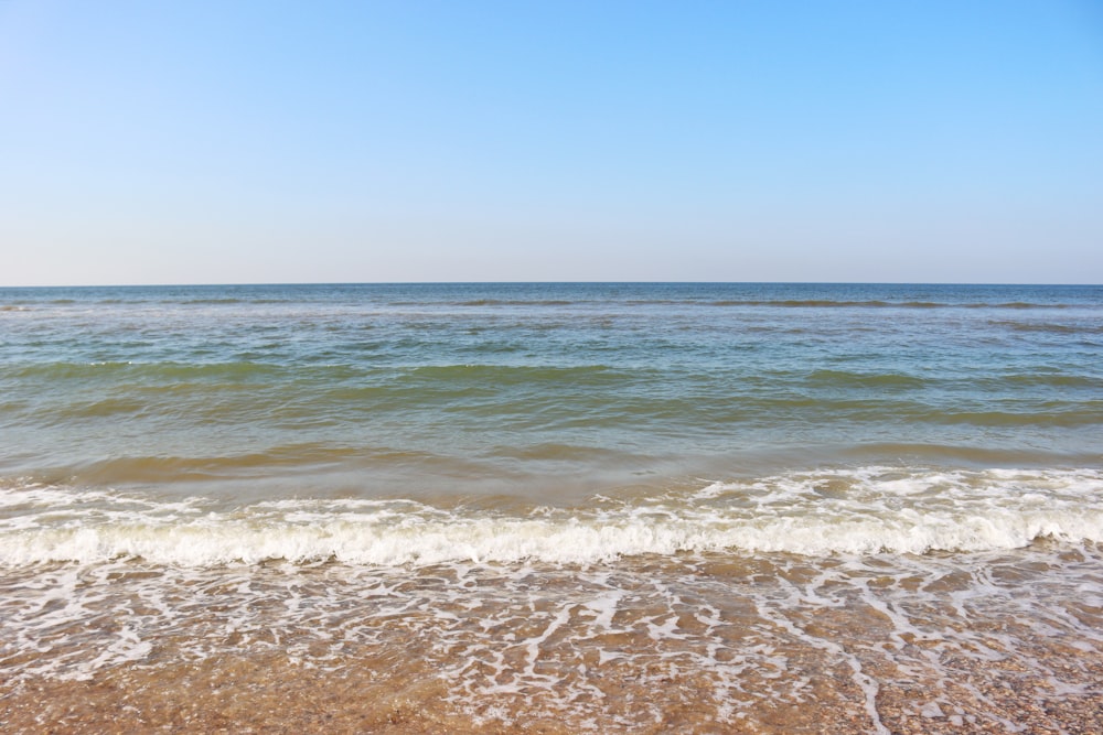 sea waves crashing on shore during daytime