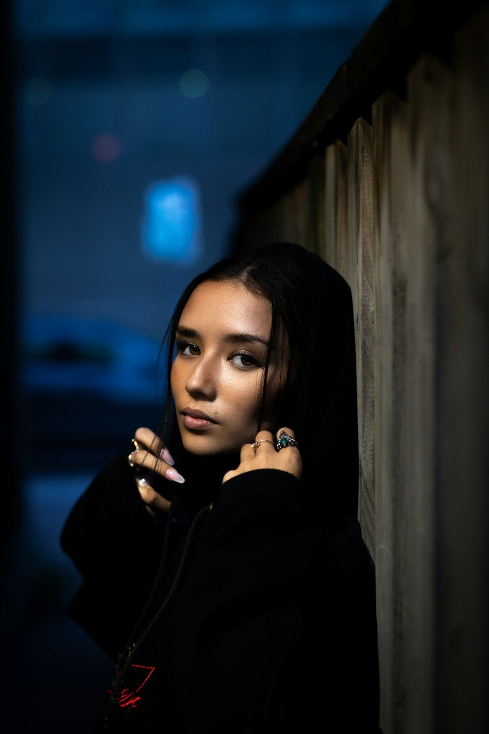 woman in black hoodie leaning on brown wall