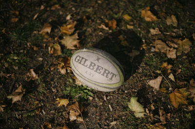 Close-up of rugby boots and ball resting on freshly cut grass under morning light
