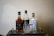 A selection of three liquor bottles arranged on a wooden tray with a crystal whiskey glass placed in front. The bottles include Jim Beam Double Oak, Kraken, and Winchester Bourbon Whiskey. The scene is set against a plain textured wall, giving a classic and refined appearance.