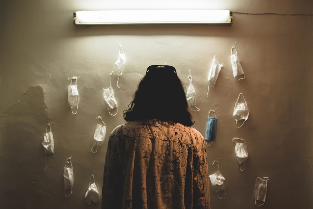 woman in brown and black coat standing in front of white wall