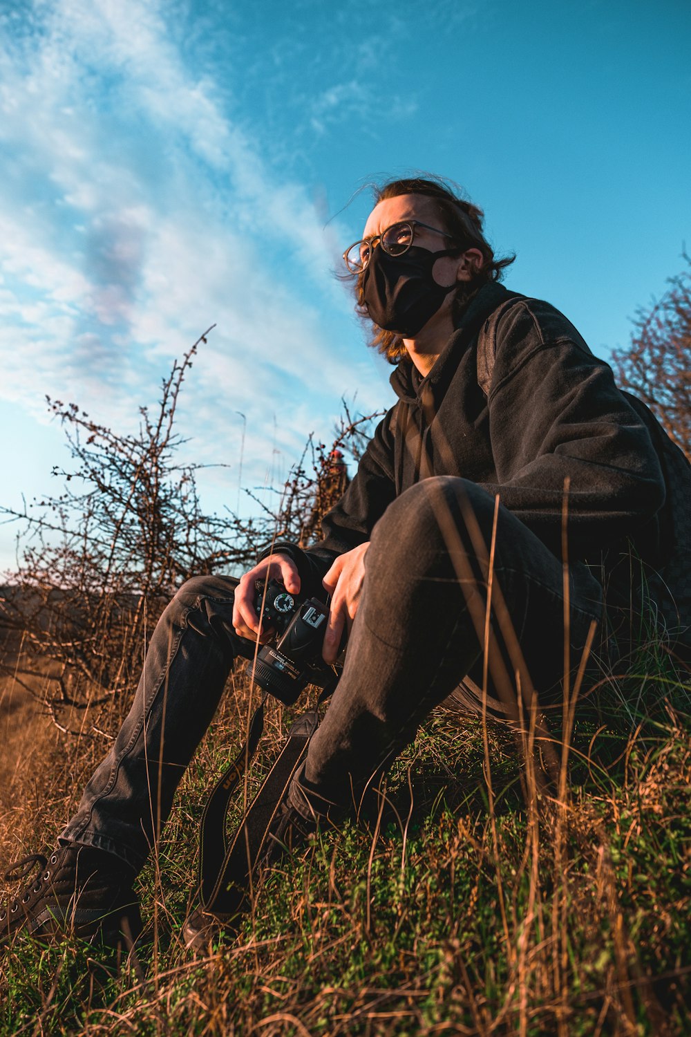 man in black jacket and gray pants sitting on grass field