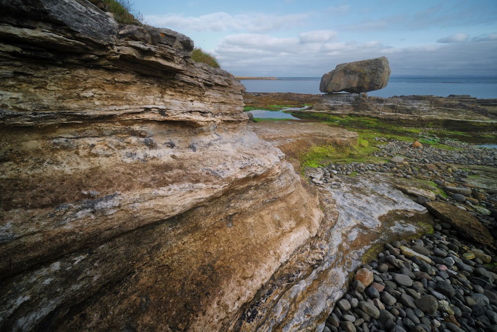 brown rock formation near body of water during daytime