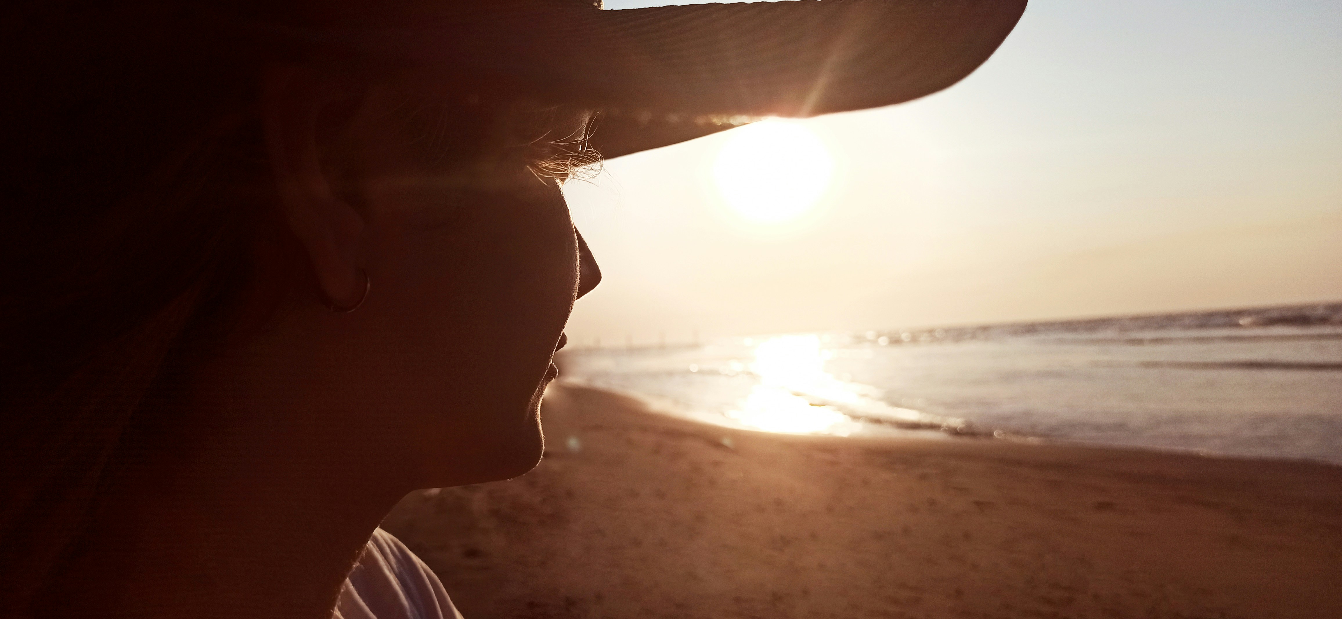 a woman wearing a hat standing on a beach