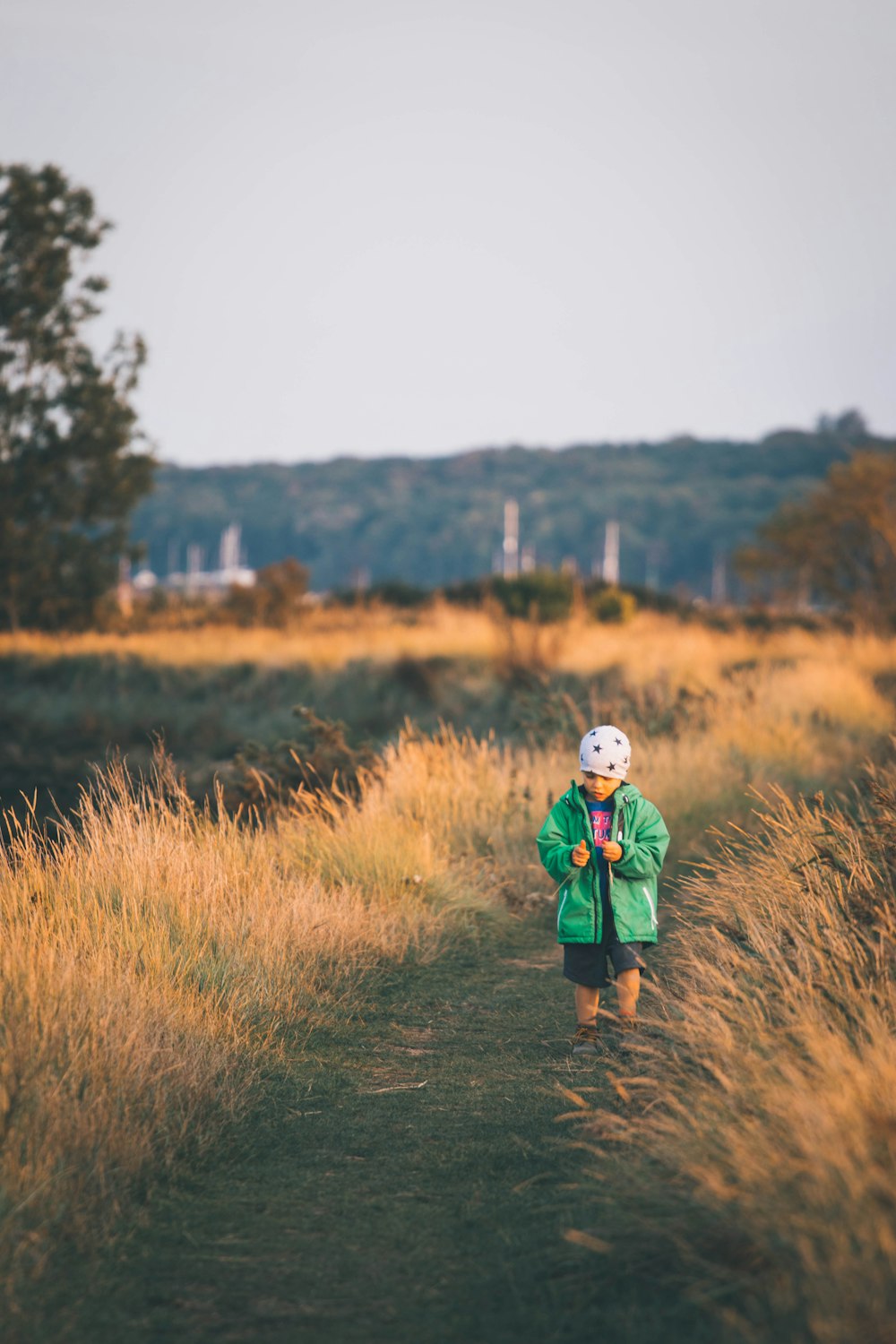 woman in green jacket standing on brown grass field during daytime