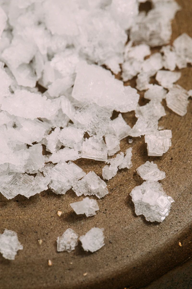 Cristaux de sel blanc sur une surface, similaires au sel pour adoucisseur d'eau