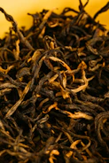 Close-up of premium loose black tea leaves in a rustic wooden bowl