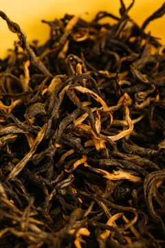 Close-up photo of tea leaves drying under sunlight in traditional method.