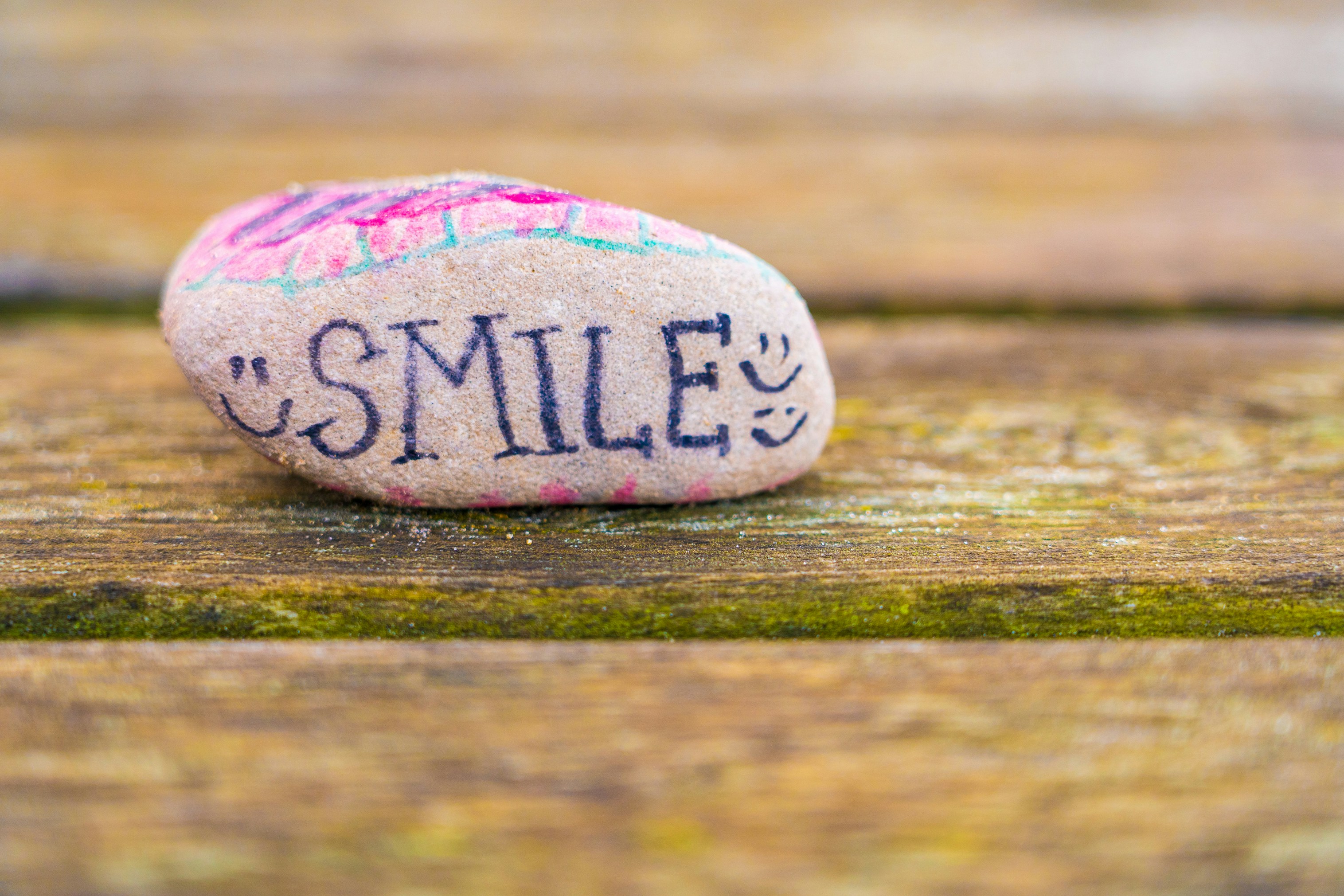 A rock with the word smile on it, surrounded by smileys, to keep spirits up during the COVID pandemic and lockdown.