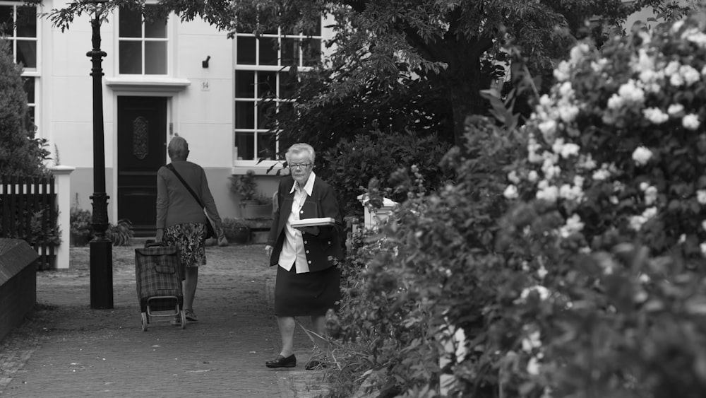 grayscale photo of 2 women standing on sidewalk