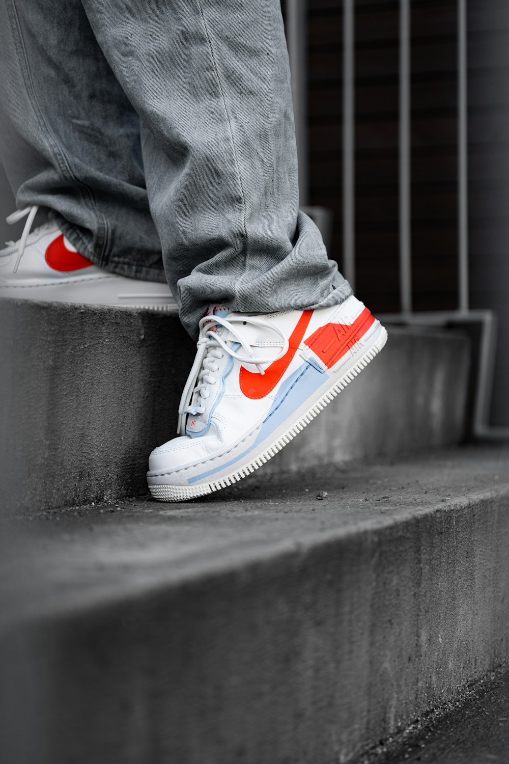 person in blue denim jeans wearing white and red nike sneakers