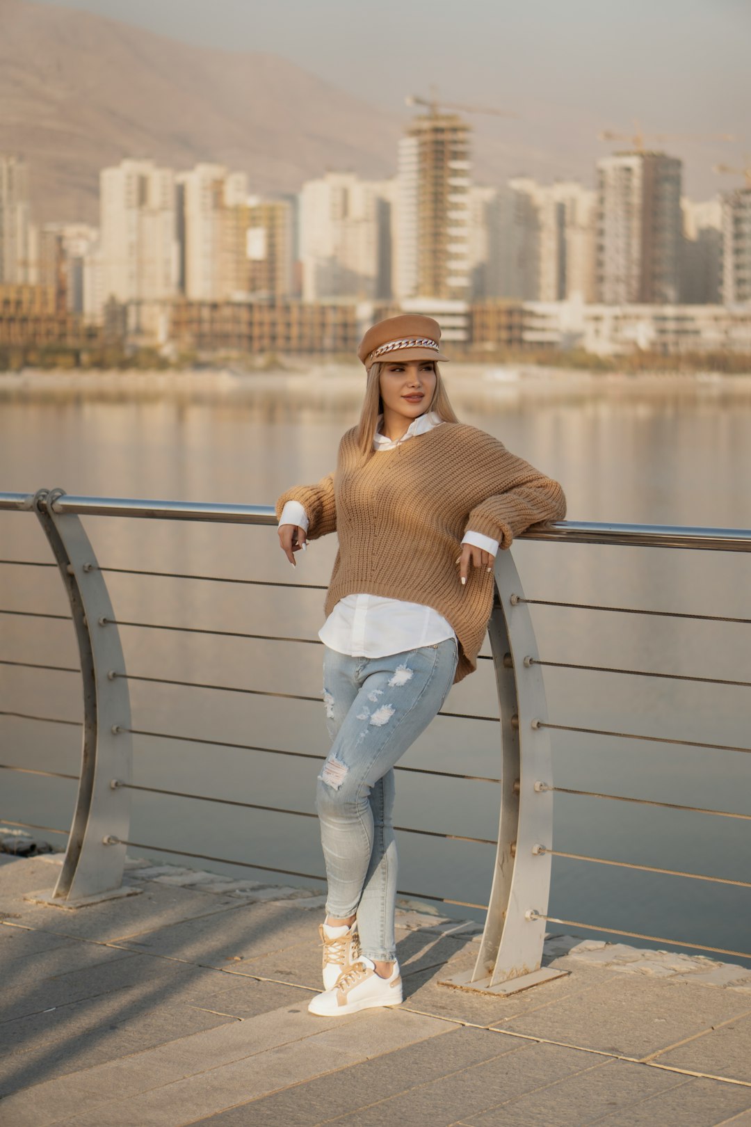 woman in brown long sleeve shirt and blue denim jeans leaning on gray metal railings