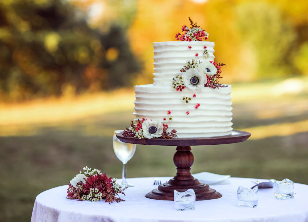 White and red floral cake on a wooden stand