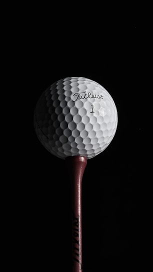 Close-up of a custom initialled golf ball stencil with embedded NFC chip resting on a golf tee.