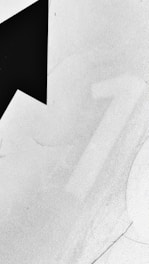 A large black arrow is prominently positioned against a textured white surface with subtle gradients. The number 1 appears faintly in the background, partially obscured.