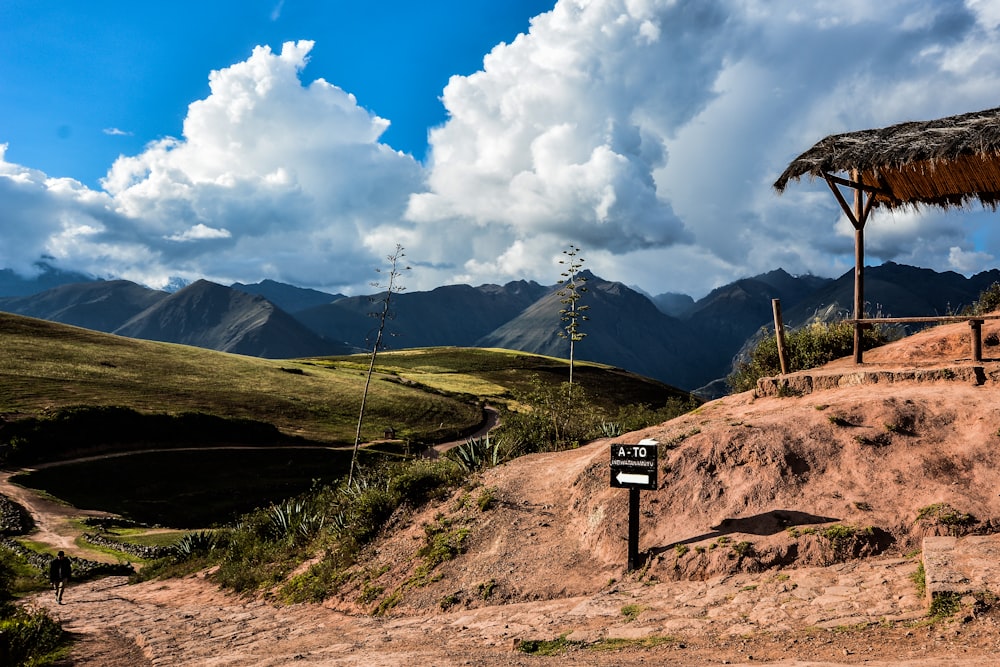 green grass field and mountain under blue sky and white clouds during daytime