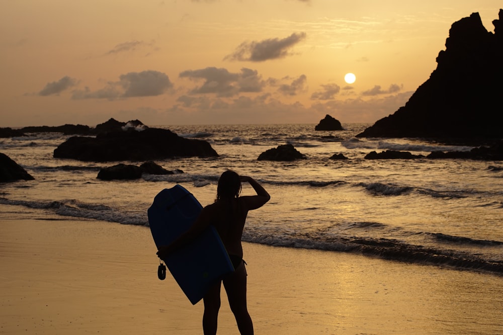 silhouette di donna in piedi sulla spiaggia durante il tramonto