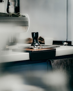 Close-up of a sleek stainless steel coffee tamper on a wooden counter