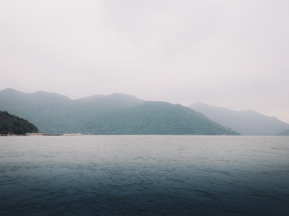 montagnes verdoyantes au bord d’un plan d’eau pendant la journée