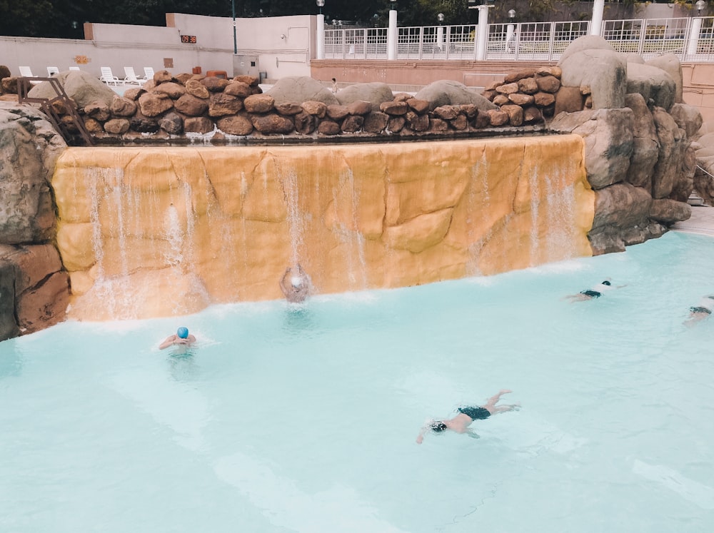 people swimming on pool during daytime