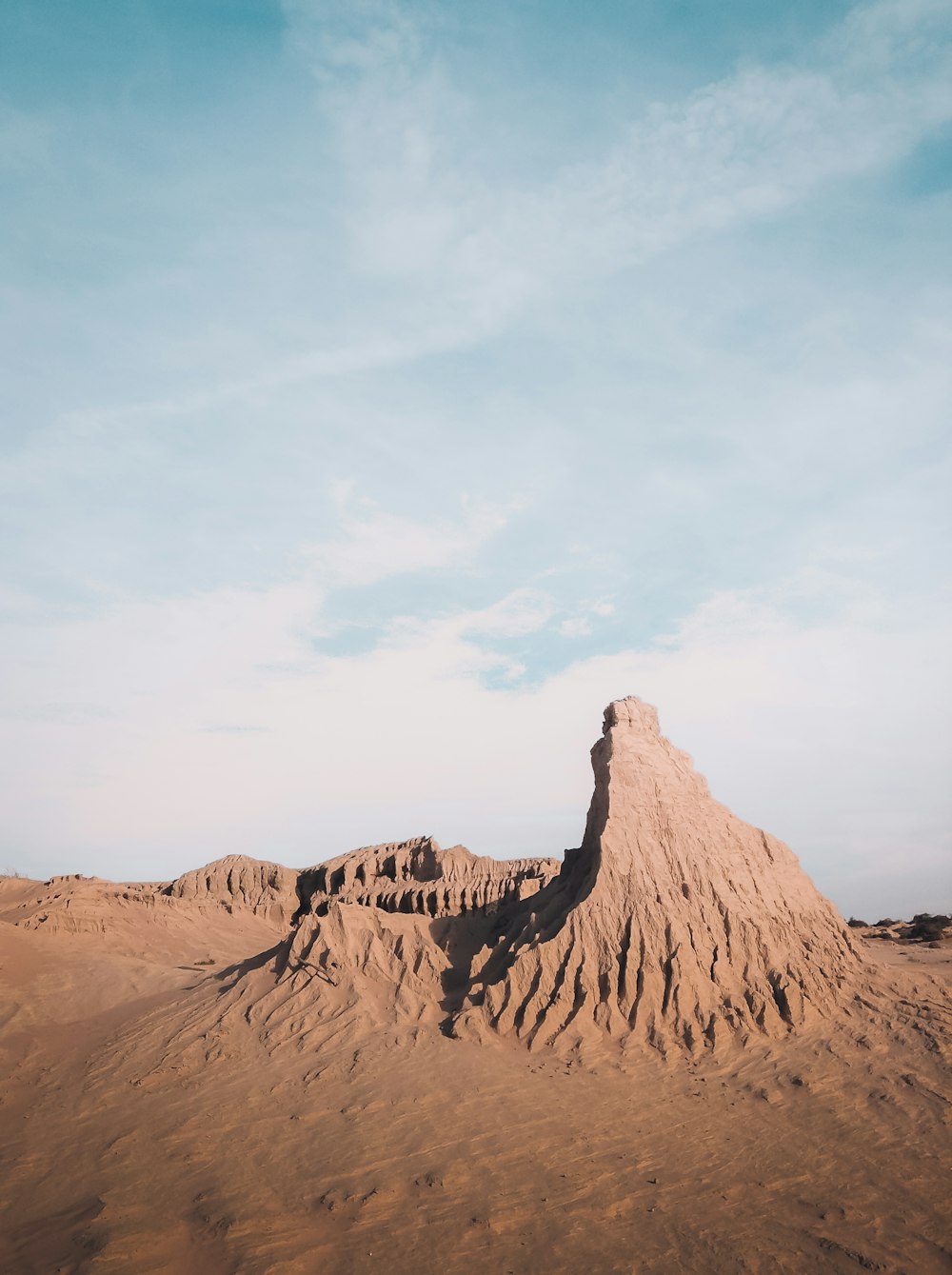 brown rock formation under white clouds during daytime