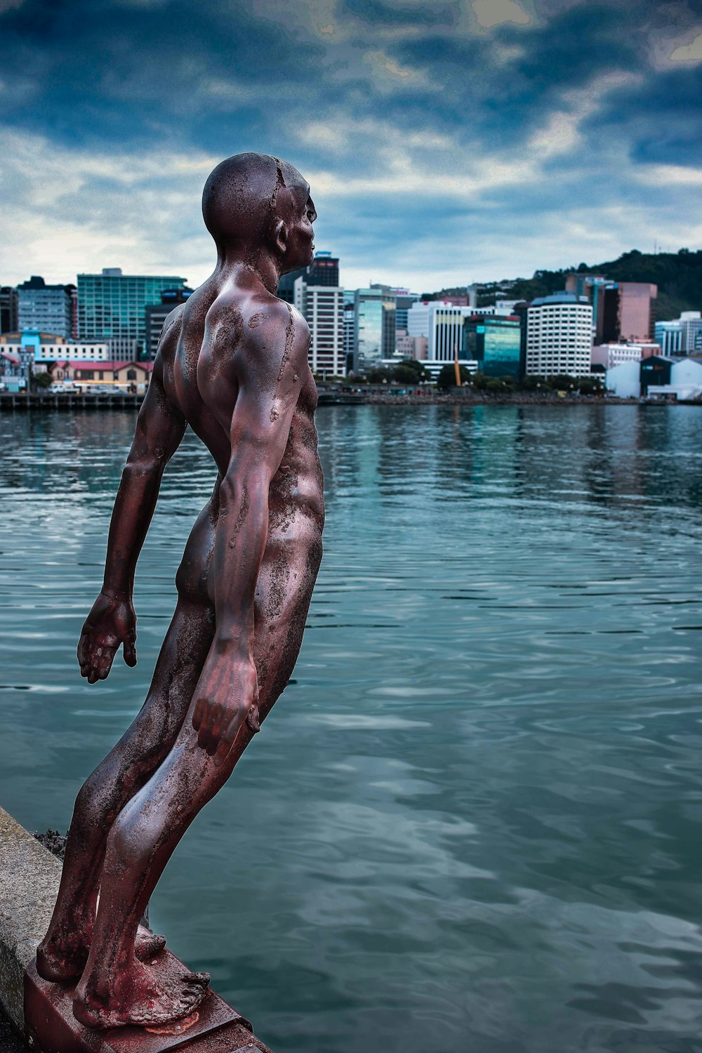 uma estátua de um homem de pé ao lado de um corpo de água