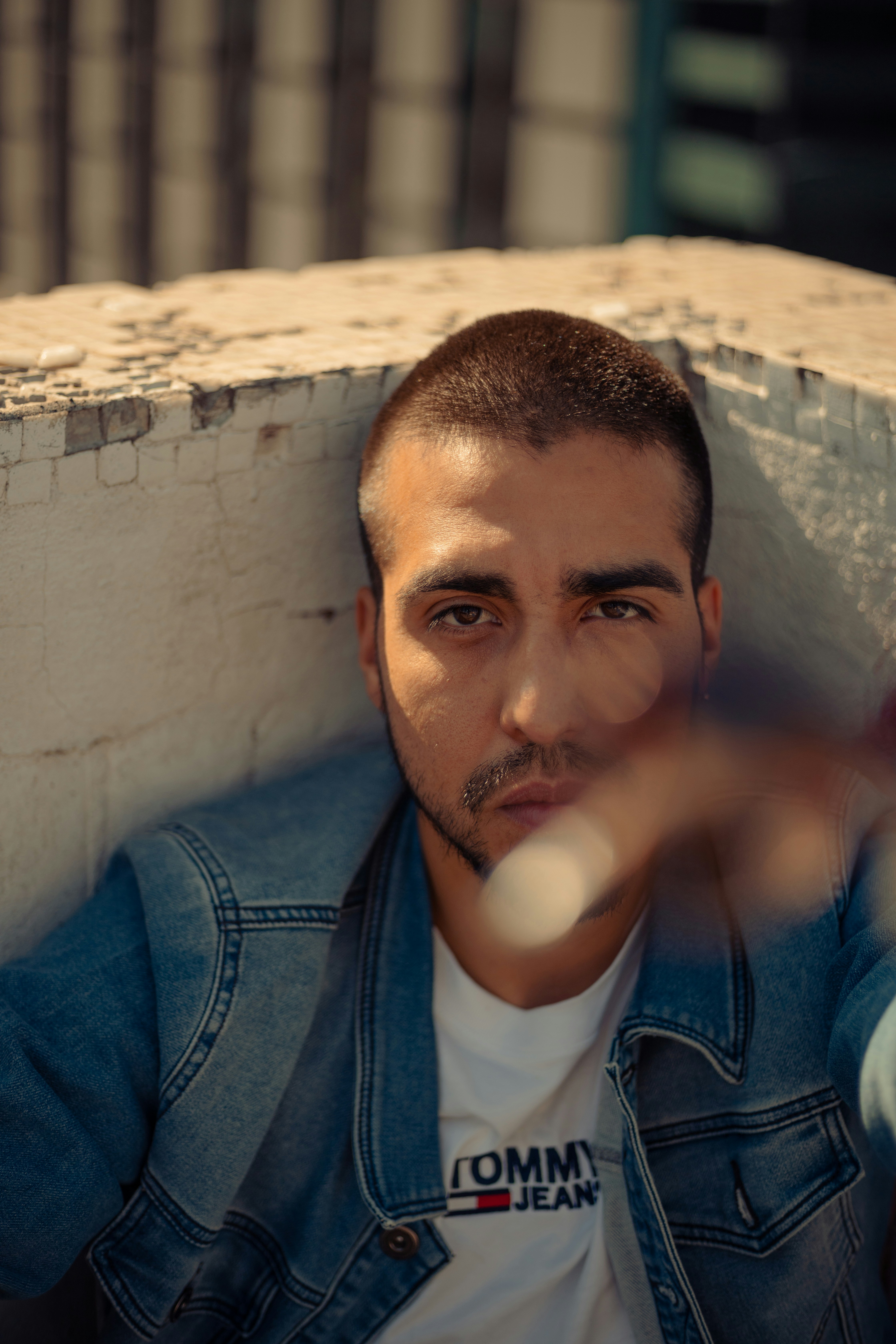 man-in-blue-denim-jacket-sitting-on-brown-concrete-bench