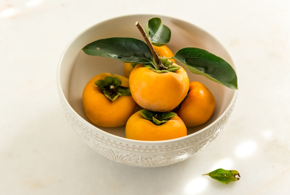 yellow and green fruits on white ceramic bowl