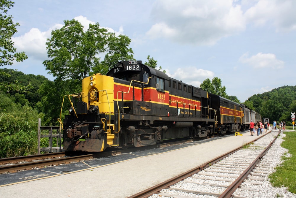yellow red and black train on rail tracks during daytime
