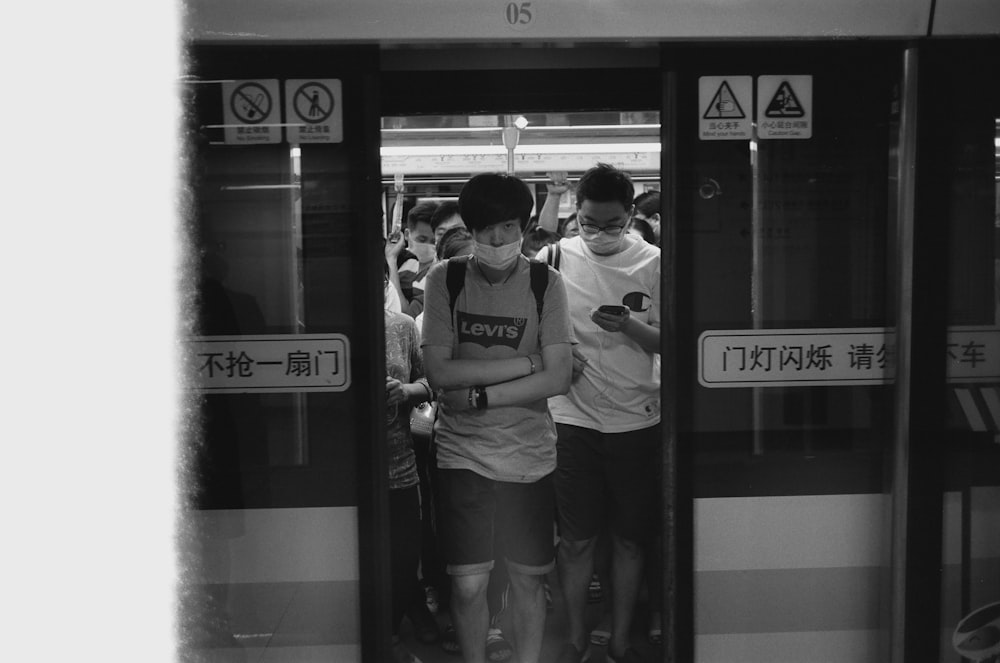 grayscale photo of man and woman standing in train