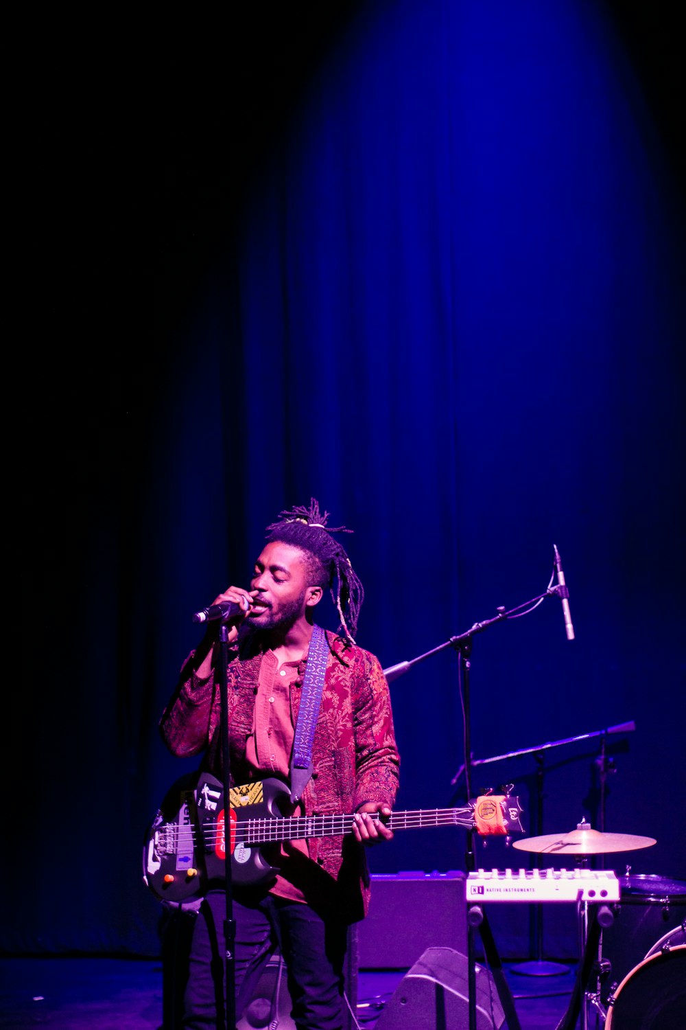 man in red and white plaid dress shirt singing on stage