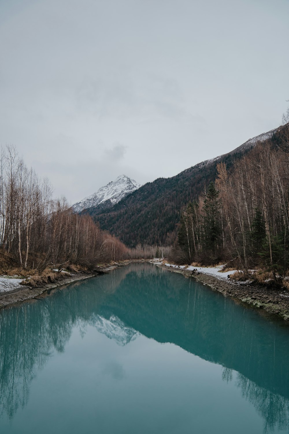 green lake surrounded by trees and mountains during daytime