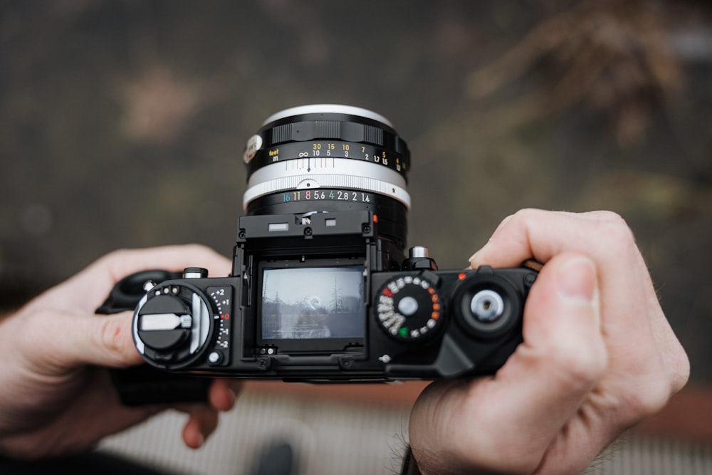 person holding black analouge camera