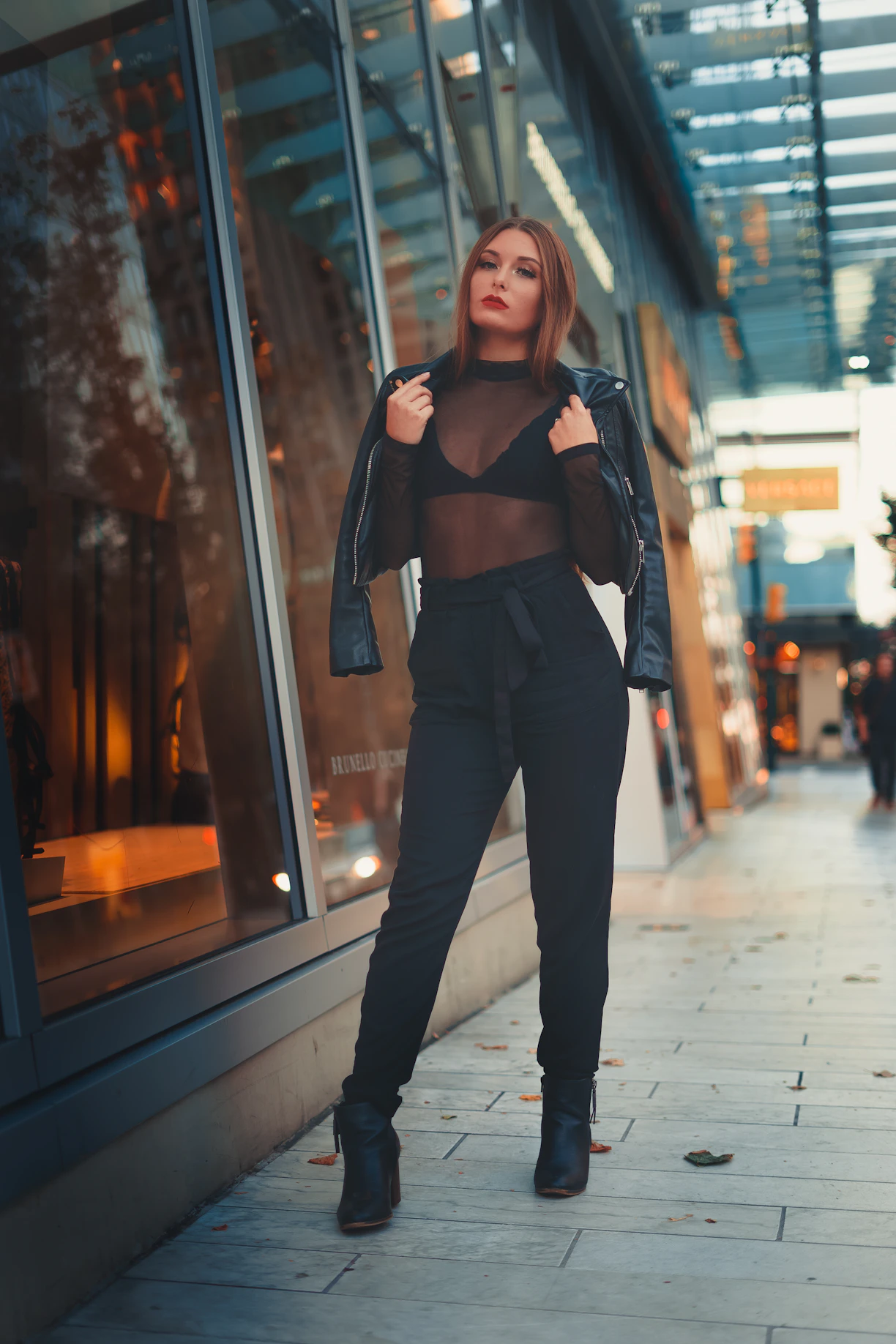 A sleek urban model wearing Lumina Apparel, walking confidently through a bustling city street at dusk.