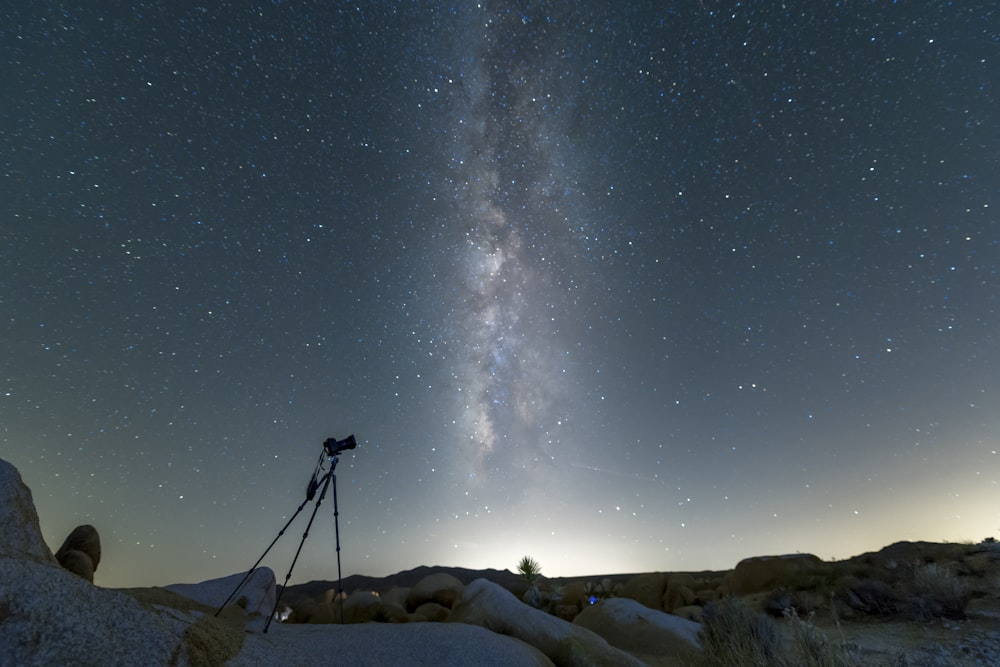 black tripod on snow covered ground under starry night