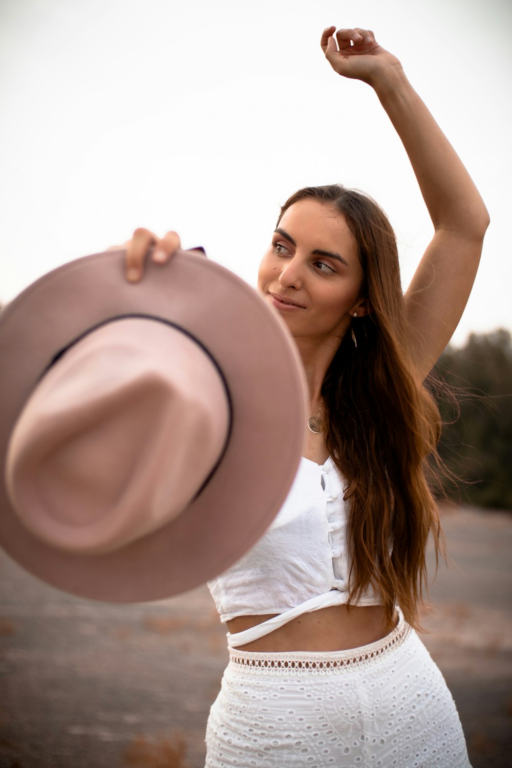 woman in white shirt holding brown hat